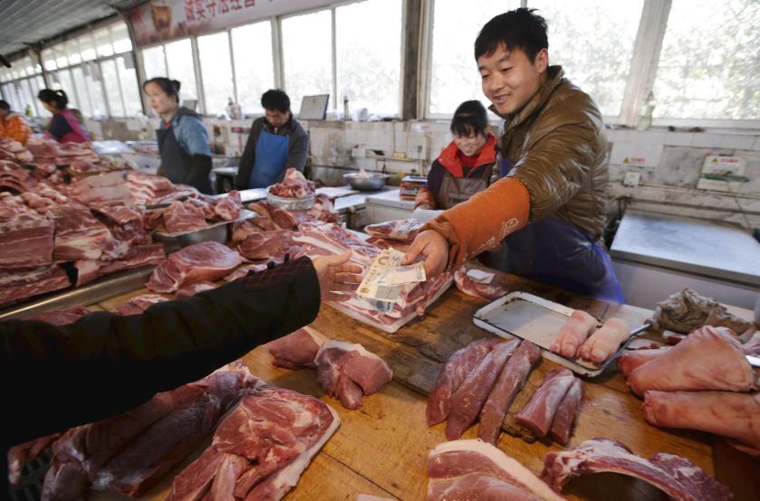 A butcher returns change to a customer at a market in Beijing